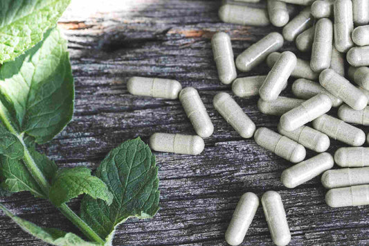Nahrungsergänzungsmittel in Kapseln ausgestreut auf rustikalem Holzhintergrund, sinnbildlich für natürliche Gesundheitsförderung und den richtigen Einsatz und Dosierung von Vitalpilzen zur Minimierung von Nebenwirkungen.