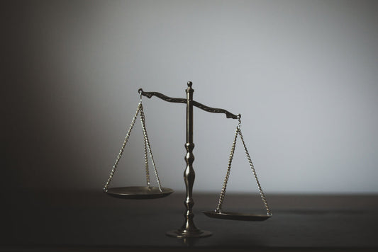 Waage der Gerechtigkeit in einem schwach beleuchteten Raum, symbolisiert juristische Ausgewogenheit, die mit Blick auf EU Hürden beim Vertrieb von medizinischen Pilzen, auf Deutsch als Vitalpilze und Heilpilze, nicht ausgewogen ist.