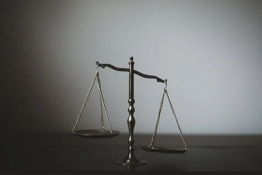 Waage der Gerechtigkeit in einem schwach beleuchteten Raum, symbolisiert juristische Ausgewogenheit, die mit Blick auf EU Hürden beim Vertrieb von medizinischen Pilzen, auf Deutsch als Vitalpilze und Heilpilze, nicht ausgewogen ist.